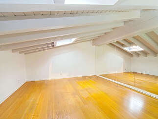 This spacious attic room boasts a stunning vaulted ceiling with exposed white beams, creating an airy and open atmosphere.