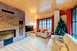 Experience cozy mountain living in this charming living room, featuring a striking stone fireplace and a warm, wood-paneled ceiling.