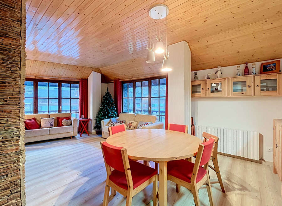Experience cozy living in this charming dining and living area, featuring a warm wooden ceiling and walls, complemented by a stone accent wall.