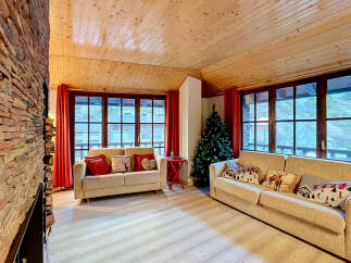 Experience cozy living in this charming mountain retreat, featuring a stunning stone fireplace and a warm, wood-paneled ceiling.