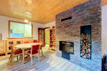 Experience cozy living in this charming dining area, featuring a rustic stone fireplace and a warm wooden ceiling.