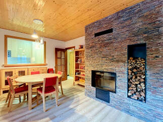 Experience cozy living in this charming dining area, featuring a rustic stone fireplace and a warm wooden ceiling.