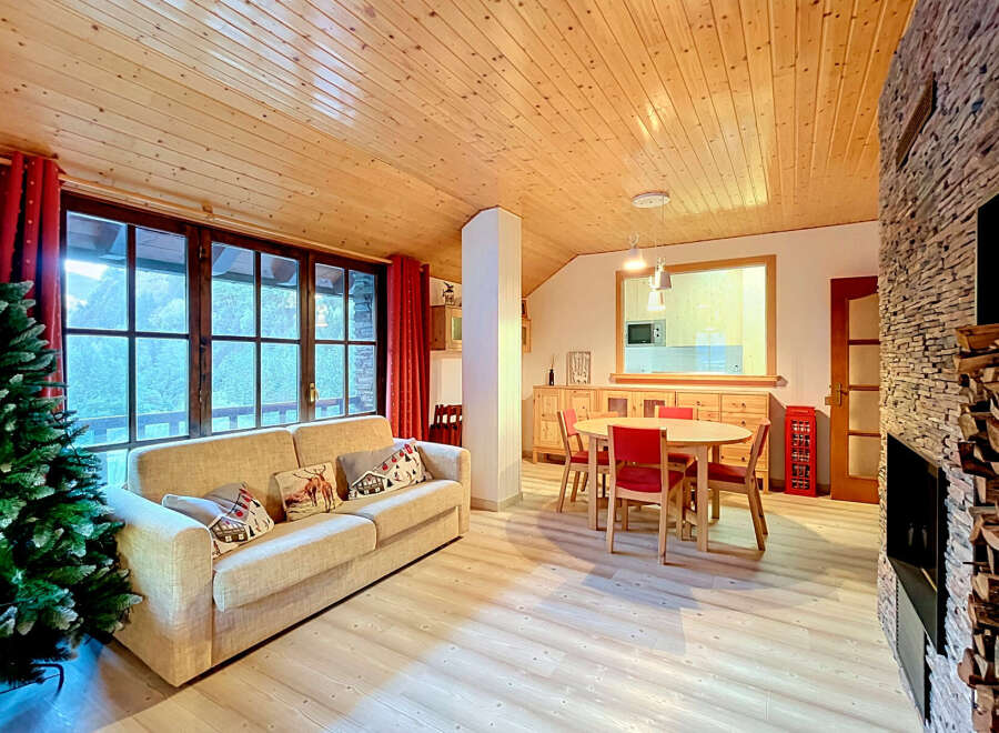 Experience cozy living in this charming mountain retreat, featuring a spacious living area with a comfortable sofa and decorative pillows, perfect for relaxing by the stone fireplace.