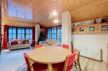 Experience cozy living in this charming mountain retreat, featuring a spacious dining area with a round wooden table and vibrant red chairs, perfect for family gatherings.