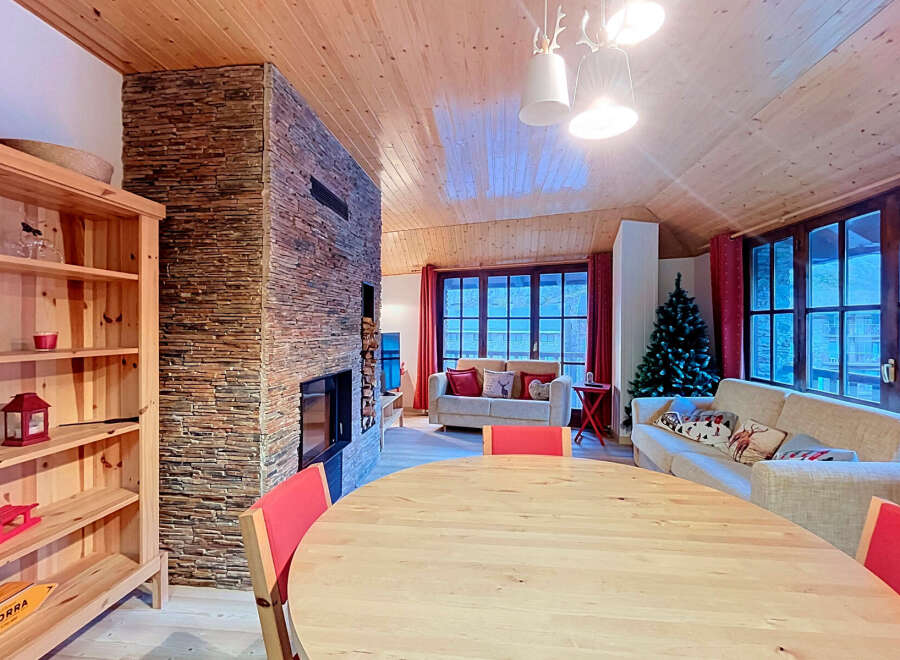 Experience cozy living in this charming mountain retreat, featuring a stunning stone fireplace and a warm, wood-paneled interior.