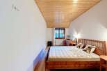 Experience cozy mountain living in this charming bedroom featuring a rustic wooden bed and a sloped, wood-paneled ceiling.