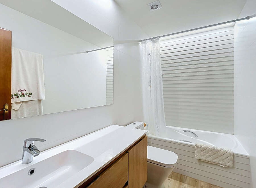 This modern bathroom features a sleek white vanity with a chrome faucet and a large mirror, perfect for your morning routine.