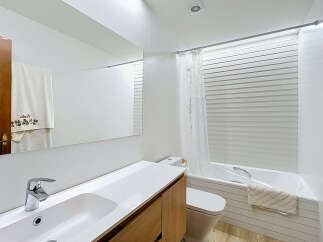 This modern bathroom features a sleek white vanity with a chrome faucet and a large mirror, perfect for your morning routine.