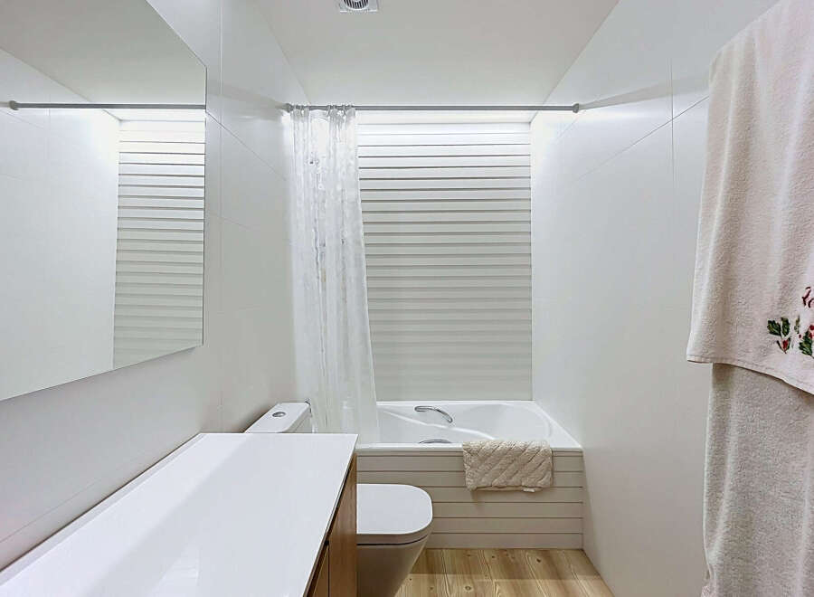 Experience modern comfort in this pristine white bathroom, featuring a sleek vanity with a large mirror and a clean-lined toilet.