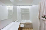 Experience modern comfort in this pristine white bathroom, featuring a sleek vanity with a large mirror and a clean-lined toilet.