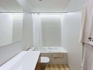 Experience modern comfort in this pristine white bathroom, featuring a sleek vanity with a large mirror and a clean-lined toilet.