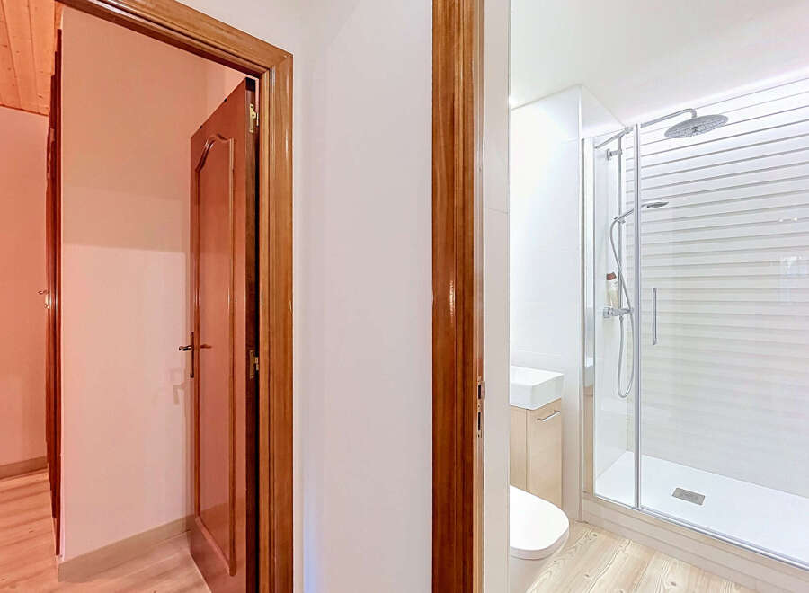 Step into a beautifully renovated bathroom featuring a sleek glass-enclosed shower with a modern rainfall showerhead.