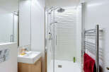 This modern bathroom features a sleek, minimalist design with white tiled walls and a spacious walk-in shower.