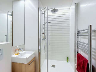 This modern bathroom features a sleek, minimalist design with white tiled walls and a spacious walk-in shower.