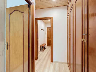 Step into this charming hallway featuring elegant wooden doors and built-in closets, offering ample storage and a warm, inviting aesthetic.