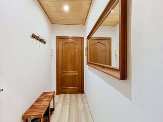 Step into this inviting entryway featuring a warm wooden bench perfect for removing shoes and a stylish coat rack to keep your essentials organized.