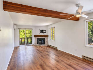 This spacious living room features a cozy brick fireplace with a wooden mantel, perfect for gathering on cooler evenings.