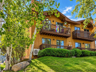 Experience comfortable living in this charming multi-story residence, featuring warm wood siding and inviting balconies perfect for enjoying the outdoors.