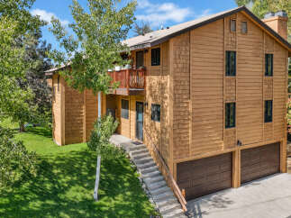 This charming wooden home features a multi-level design with a welcoming balcony and a spacious two-car garage.