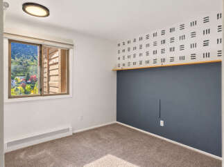 This charming bedroom features a large window offering scenic views of the surrounding mountains and greenery.