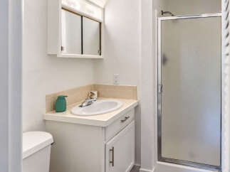 This bathroom features a clean and functional design with a white vanity and sink, complemented by a beige tiled backsplash.