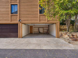 This property features a spacious two-car garage with one side open, revealing a clean interior with shelving and a bicycle.