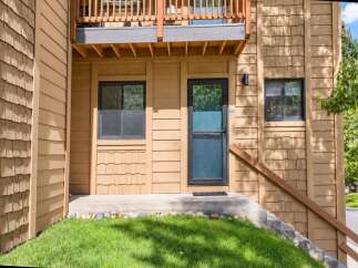 Discover this charming property featuring a welcoming entrance with a dark-framed door and a screen door, flanked by two windows.