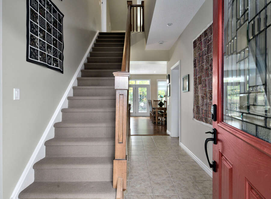 Step into a welcoming entryway featuring a plush carpeted staircase and elegant wall decor.