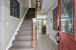 Step into a welcoming entryway featuring a plush carpeted staircase and elegant wall decor.