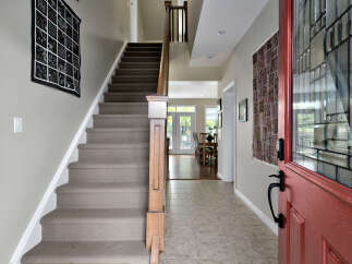 Step into a welcoming entryway featuring a plush carpeted staircase and elegant wall decor.
