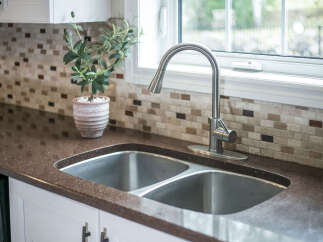 Experience the elegance of this kitchen, featuring a stunning dual-basin stainless steel sink complemented by a sleek, modern faucet.