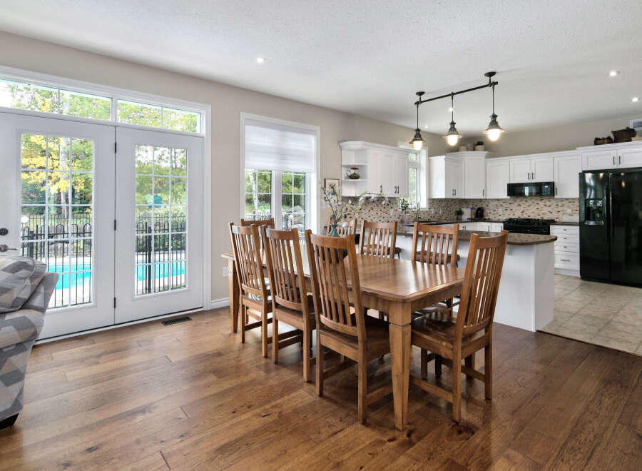 This spacious open-concept home features a bright dining area with a large wooden table, perfect for family gatherings.
