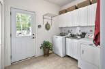 This laundry room features a white Maytag washer and dryer set, complemented by white cabinetry and a subway tile backsplash.