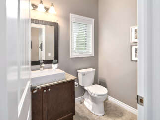 This powder room features a modern vessel sink atop a dark wood vanity with granite countertops, complemented by a sleek chrome faucet.