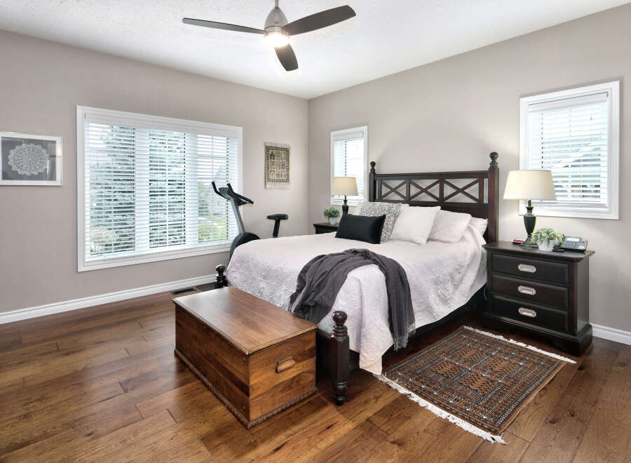 This inviting bedroom features a spacious king-size bed with a dark wood headboard, complemented by plush white bedding and decorative pillows.