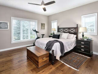 This inviting bedroom features a spacious king-size bed with a dark wood headboard, complemented by plush white bedding and decorative pillows.