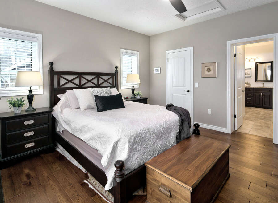 This master bedroom offers a serene retreat with its elegant dark wood furniture, including a stately bed frame and matching nightstands.