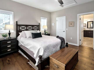 This master bedroom offers a serene retreat with its elegant dark wood furniture, including a stately bed frame and matching nightstands.
