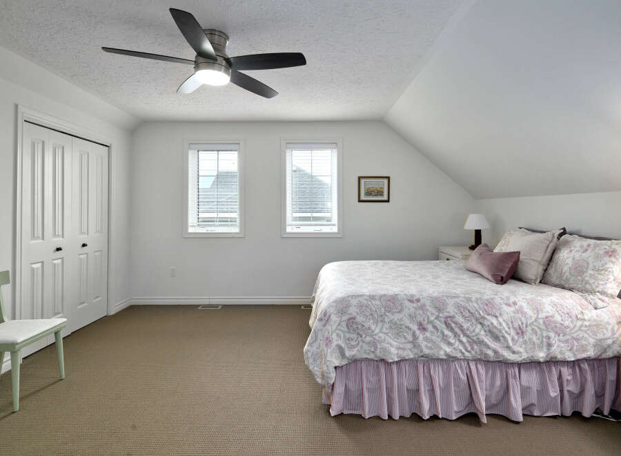 This charming bedroom features a comfortable queen-size bed adorned with a beautiful paisley comforter and a pink pinstripe bed skirt.