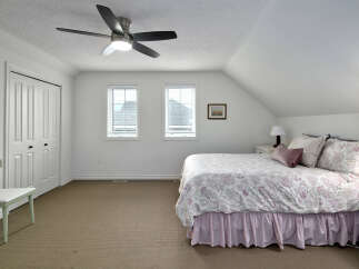 This charming bedroom features a comfortable queen-size bed adorned with a beautiful paisley comforter and a pink pinstripe bed skirt.