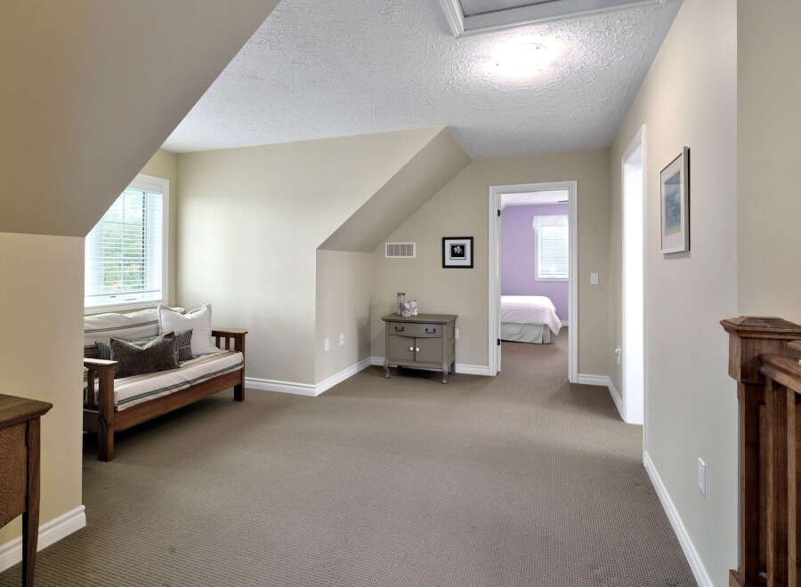 This charming attic space offers a cozy seating area with a daybed and decorative pillows, perfect for relaxation.