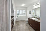 This spacious bathroom features a large vanity with ample storage, a comfortable toilet, and a bright window with blinds.