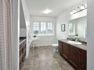This spacious bathroom features a large vanity with ample storage, a comfortable toilet, and a bright window with blinds.