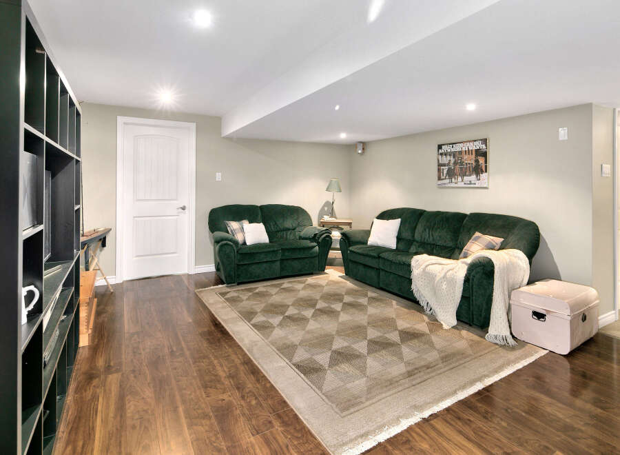 This inviting basement living area features two plush green sofas, perfect for relaxing or entertaining.