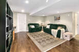 This inviting basement living area features two plush green sofas, perfect for relaxing or entertaining.