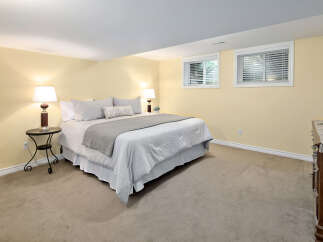 Discover comfort and style in this inviting bedroom, featuring a plush king-sized bed adorned with soft, neutral linens and a cozy throw.