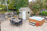 Enjoy outdoor living with this spacious patio featuring a dining set and a luxurious hot tub, perfect for relaxation and entertaining.