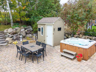 Enjoy outdoor living with this spacious patio featuring a dining set and a luxurious hot tub, perfect for relaxation and entertaining.