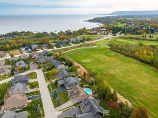 Experience luxury living in this stunning aerial view of a residential neighborhood nestled beside a golf course and overlooking a serene lake.