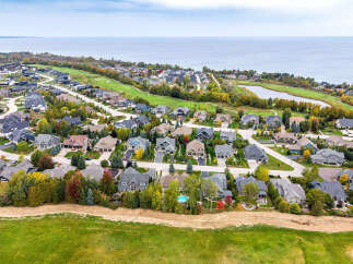 Experience luxury living in this stunning aerial view of a modern residential community nestled beside a serene lake and golf course.